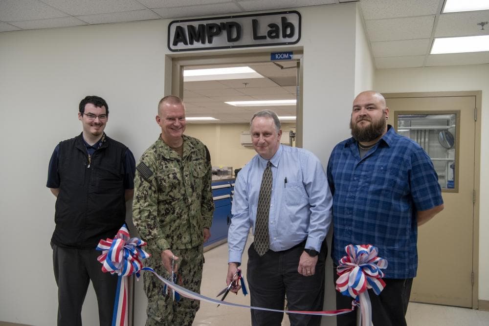 Photo By Devin M Pisner | From left: Scott Ziv, a mechanical engineer in Carderock’s Additive Manufacturing Branch; Capt. Todd Hutchison, commanding officer; Paul Young, head of the Fabrication and Technical Support Division; and Ryan Franke, a technician in Carderock’s Subtractive and Additive Manufacturing Branch, cut the ribbon during the grand opening of Carderock’s new Advanced Manufacturing Prototyping (AMP) Lab at Naval Surface Warfare Center, Carderock Division in West Bethesda, Md., on June 23, 2022. (U.S. Navy photo by Devin Pisner)